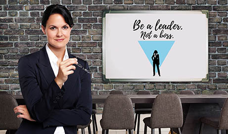 femme à côté d'un tableau avec le texte Be a leader not a boss