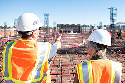 un homme et une femme avec un casque de protection et une tenue haute visibilité sur un chantier